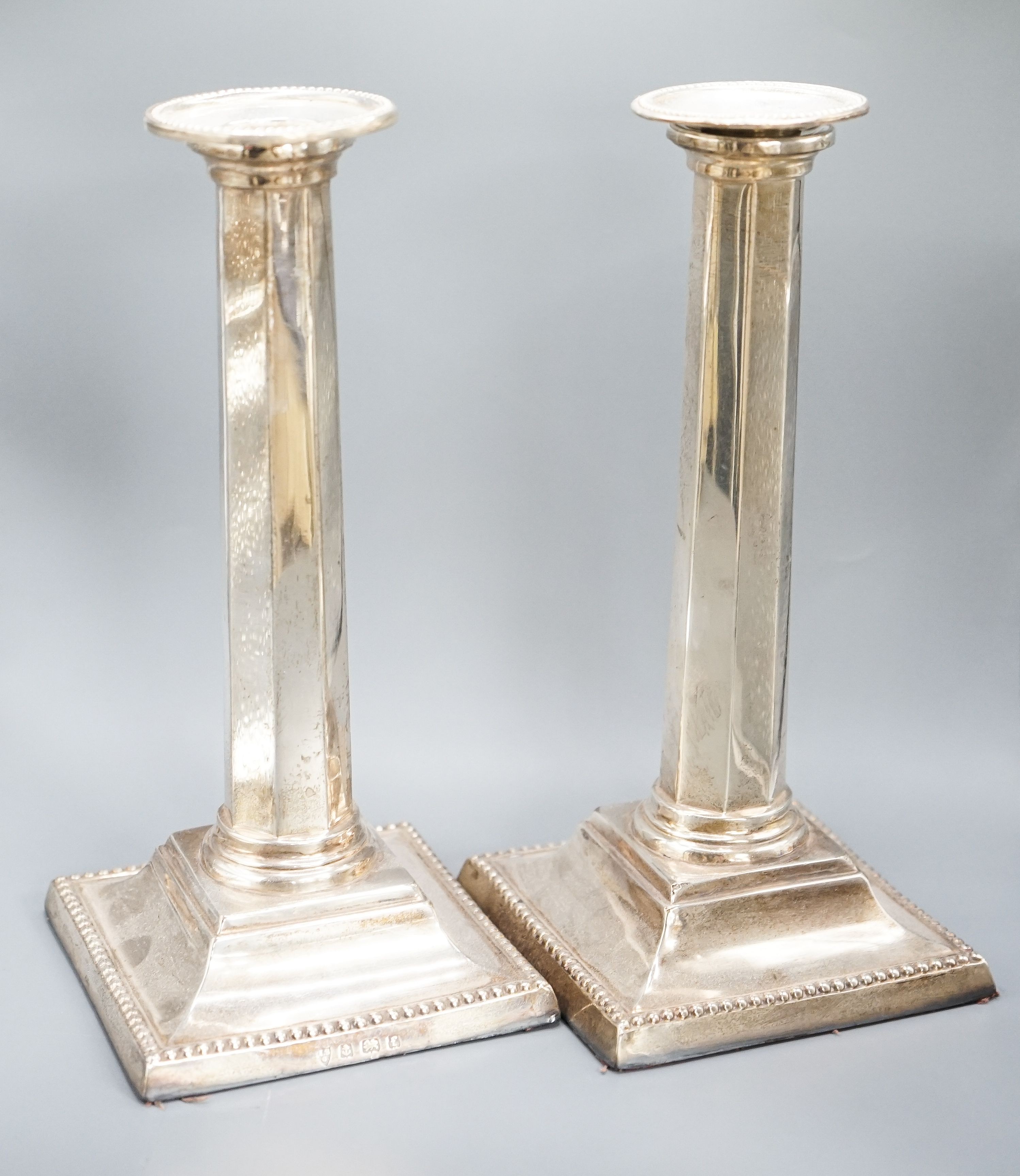 A pair of Edwardian silver candlesticks, with panelled columns, Birmingham, 1905, 20.8cm, weighted.